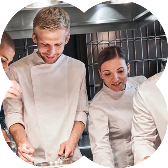 Küchenteam in weißen Kochjacken beim Kochen